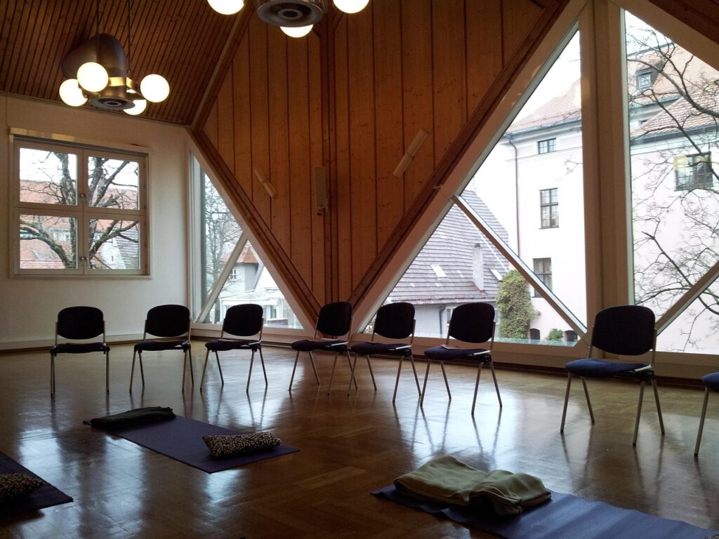 Seminarraum mit Meditationsmatten und Stuhlkreis vor großen Fenstern – ein Ort, der Klarheit, Präsenz nach energetischer Reinigung ausstrahlt